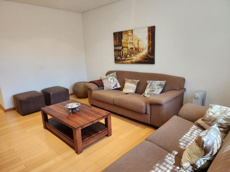 A comfortable living room featuring light-toned laminate flooring and neutral wall finishes, providing a versatile space for relaxation.