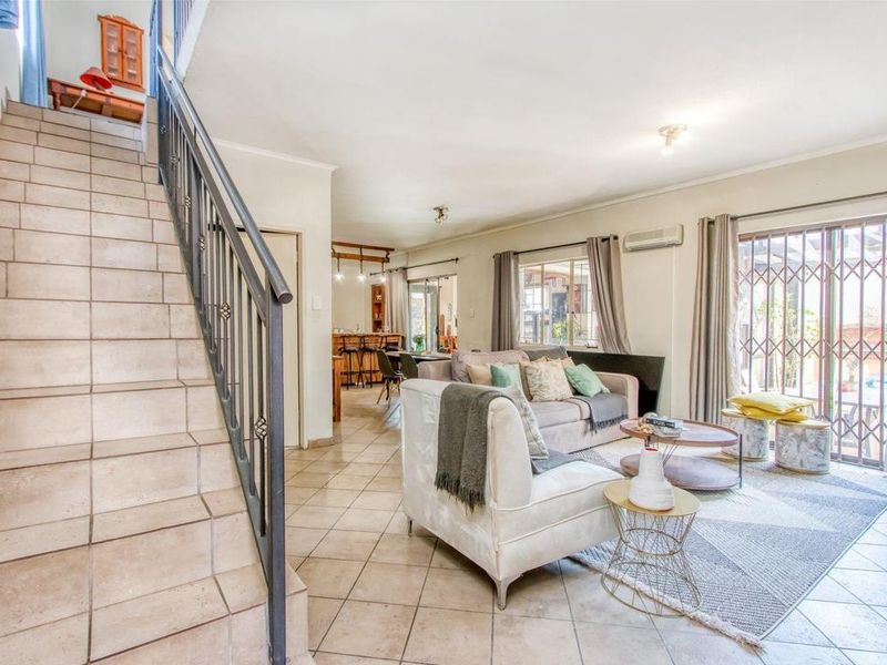 Spacious open-plan living area featuring tiled flooring, a staircase with wrought iron railing, and sliding doors leading to the exterior.