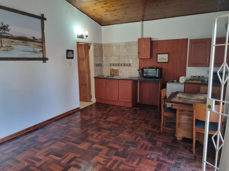 A functional kitchen area featuring timber ceilings, parquet flooring, and built-in cabinetry with a tiled splashback.