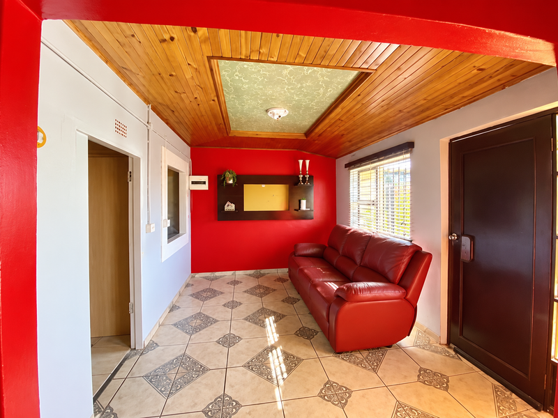 A living room featuring ceramic tiled flooring, a timber-paneled ceiling with a decorative central panel, and built-in wall shelving.
