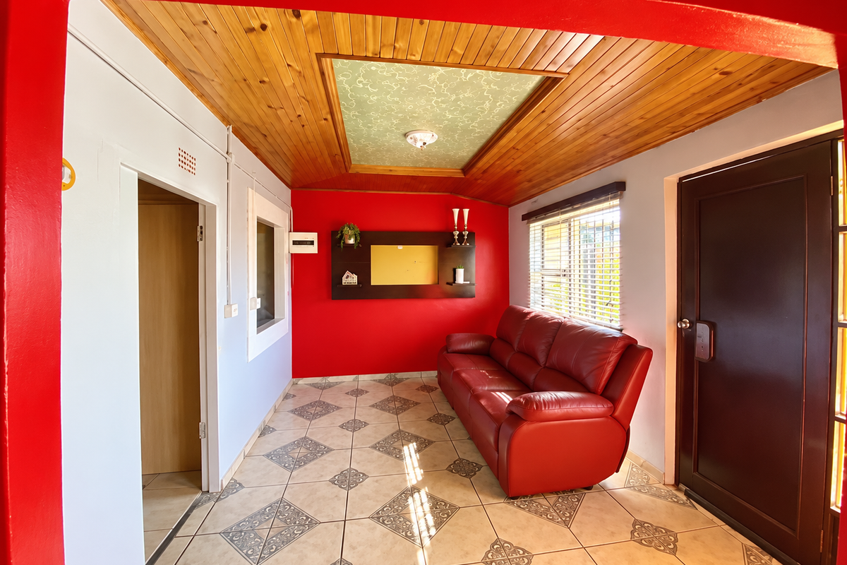 A living room featuring ceramic tiled flooring, a timber-paneled ceiling with a decorative central panel, and built-in wall shelving.