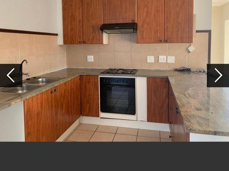 A functional kitchen featuring wood-look laminate cabinetry, granite countertops, a built-in oven with gas hob, and a tiled backsplash.