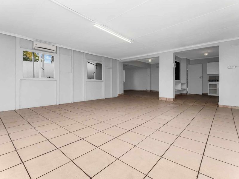 Spacious open-plan living area featuring tiled flooring, split-system air conditioning, and a small integrated kitchenette area.