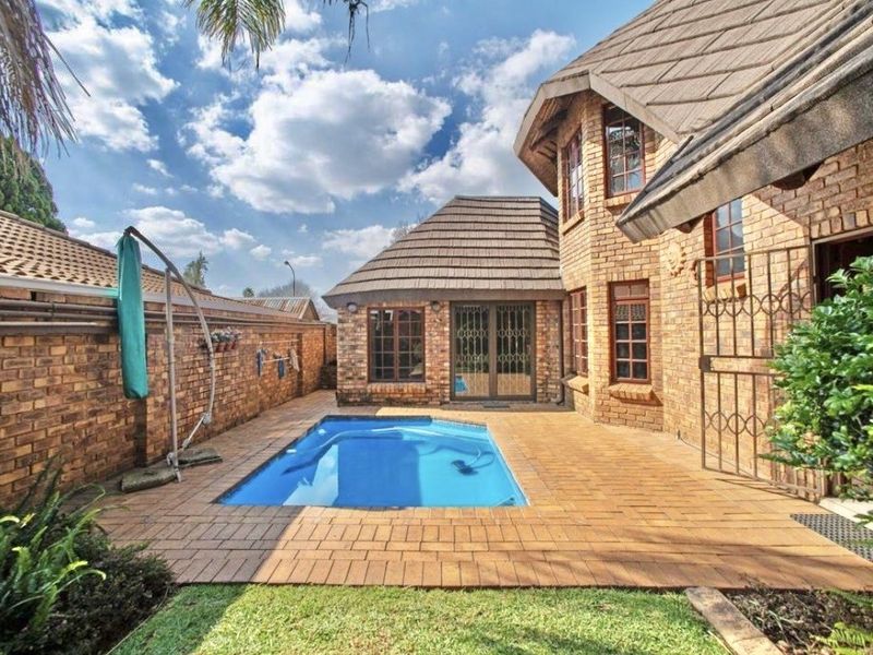 A private outdoor pool area featuring face brick architecture, paved surround, and secure boundary walls in a well-maintained cluster setting.