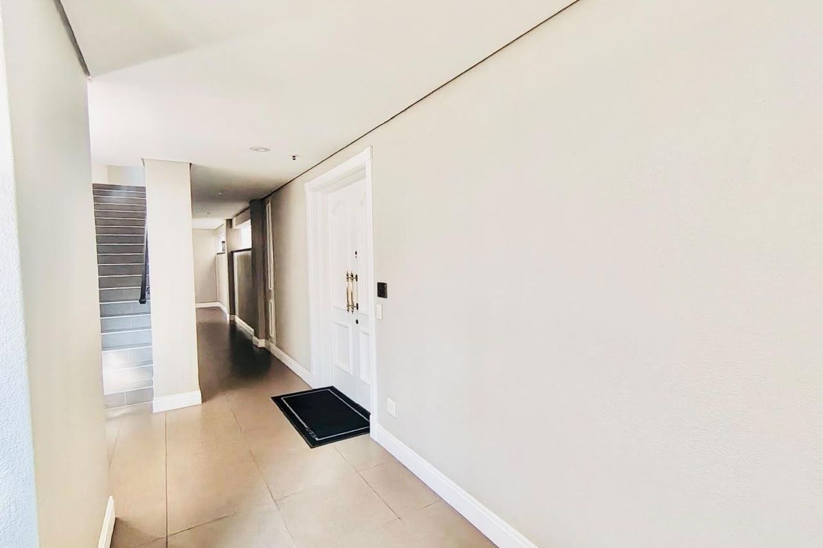 A bright and spacious entrance hall featuring neutral tiled flooring, clean white walls, and a staircase leading to the upper level.
