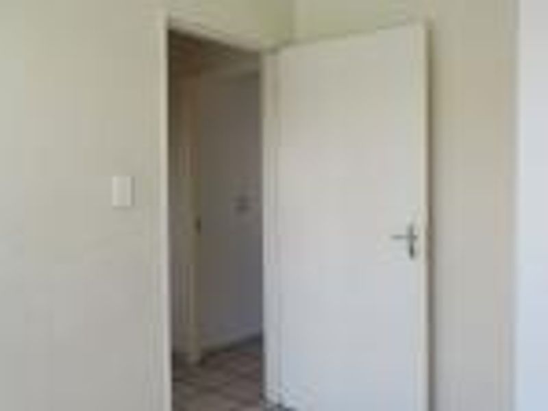 A simple interior view of a hallway featuring a standard door and neutral wall finishes.