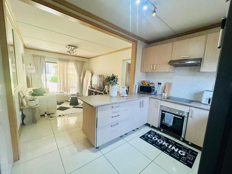 Open-plan kitchen and living area featuring modern cabinetry, granite countertops, integrated appliances, and large format floor tiles leading to a patio.