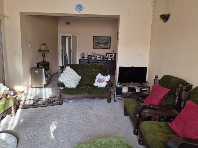 A spacious living room featuring a combination of tiled and carpeted flooring, an architectural archway, and wall-mounted lighting fixtures.