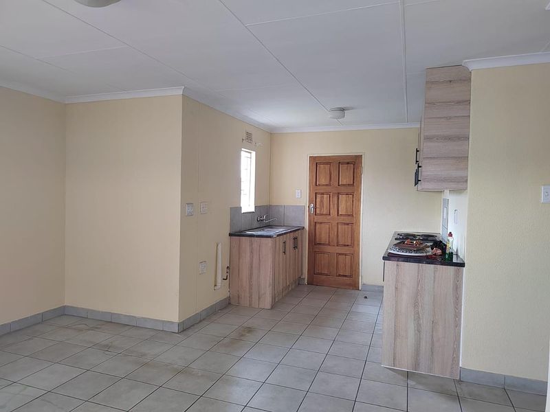 A functional kitchen area featuring built-in cabinetry, laminate countertops, a stainless steel sink, and tiled flooring, offering a blank canvas for updates.