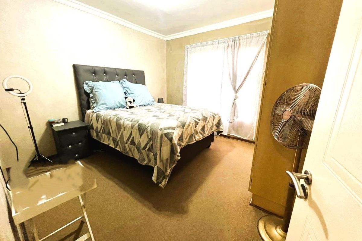 A bedroom featuring carpeted flooring, cove cornicing, and a sliding door providing access to natural light.