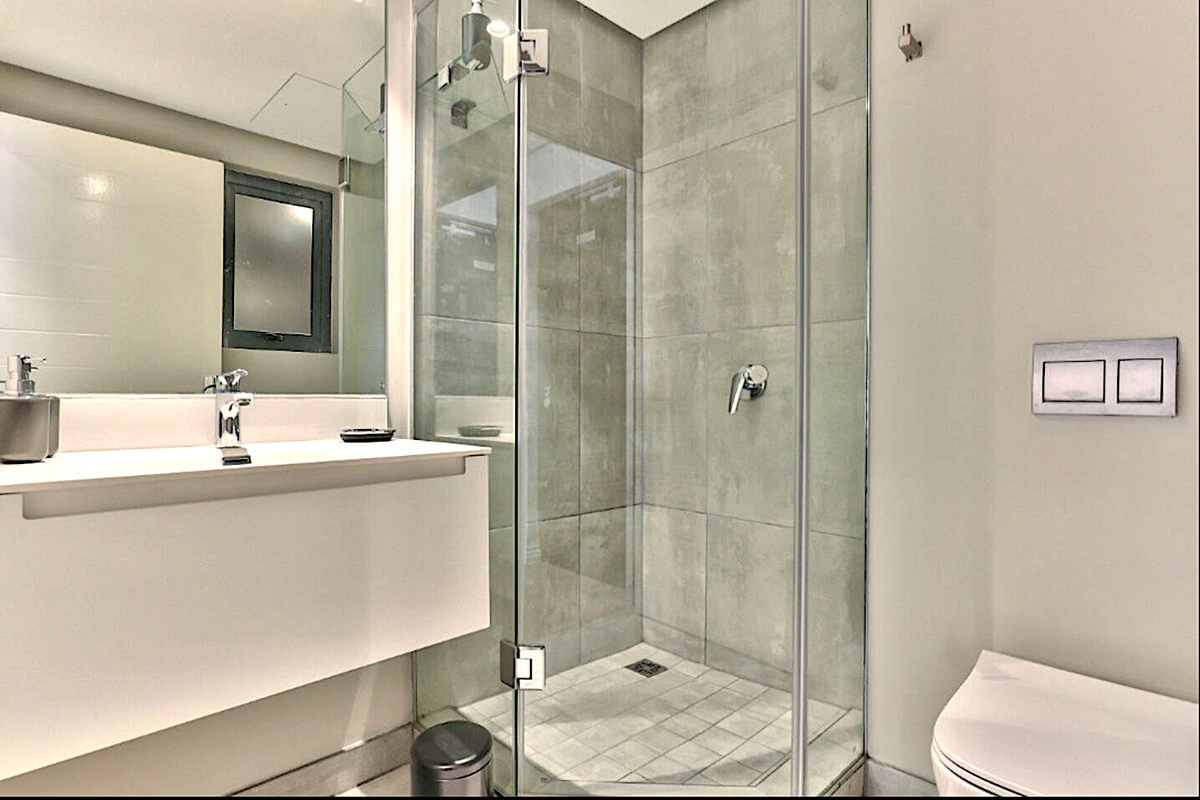 Modern bathroom featuring a wall-mounted vanity, glass-enclosed shower with tiled finishes, and a wall-hung toilet with a concealed cistern.