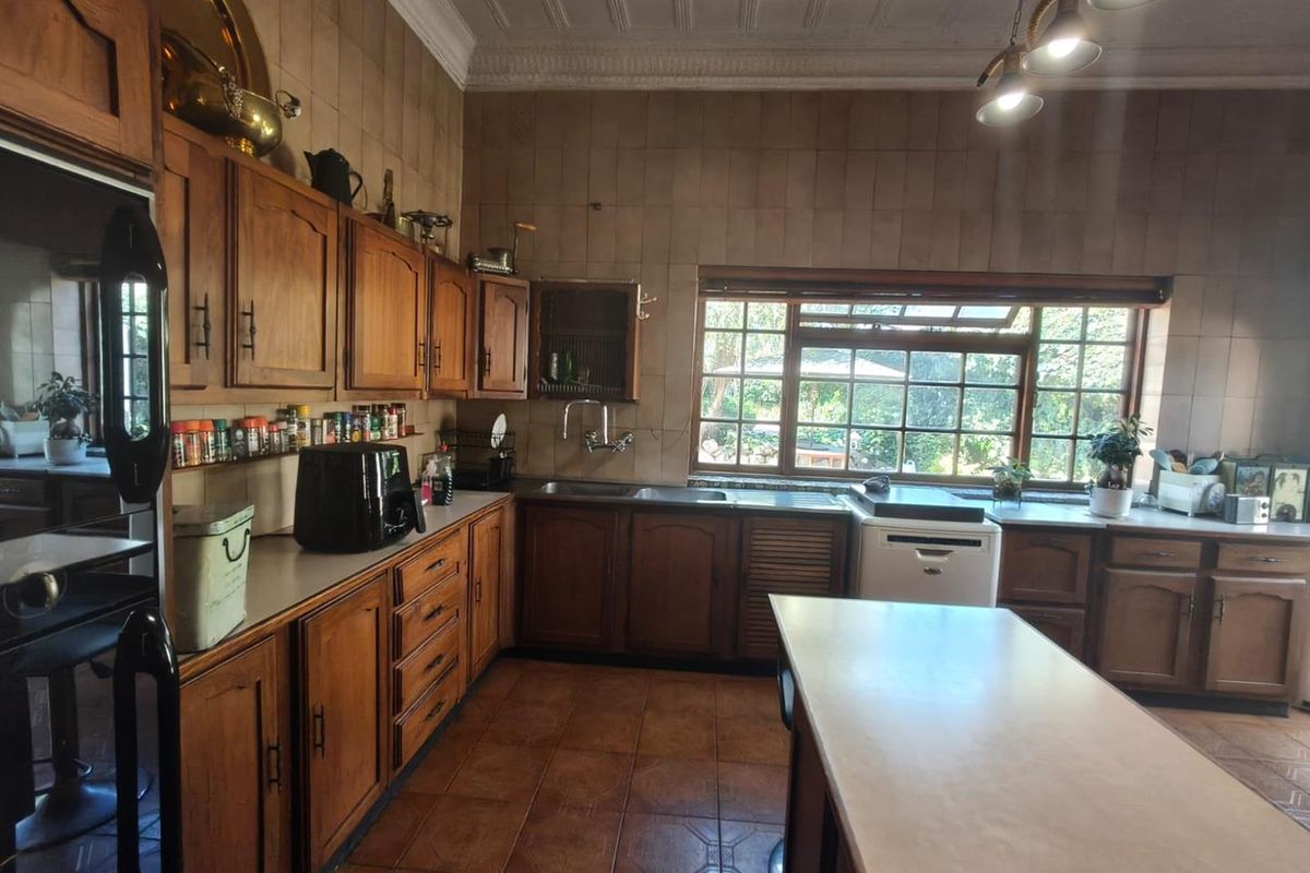 A traditional kitchen featuring extensive wooden cabinetry, tiled backsplash, and tiled flooring, offering a functional layout with ample counter space and natural light.