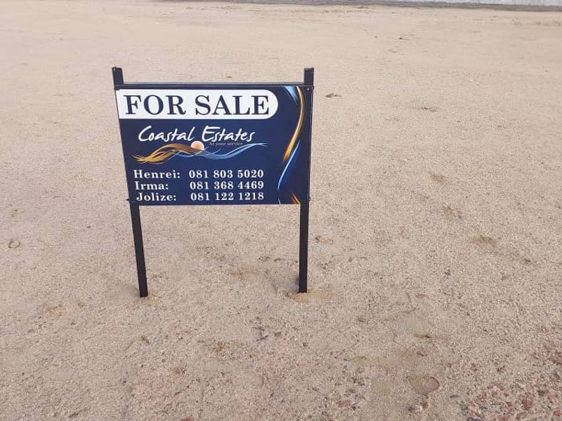 A vacant residential plot of land featuring a real estate for sale sign.