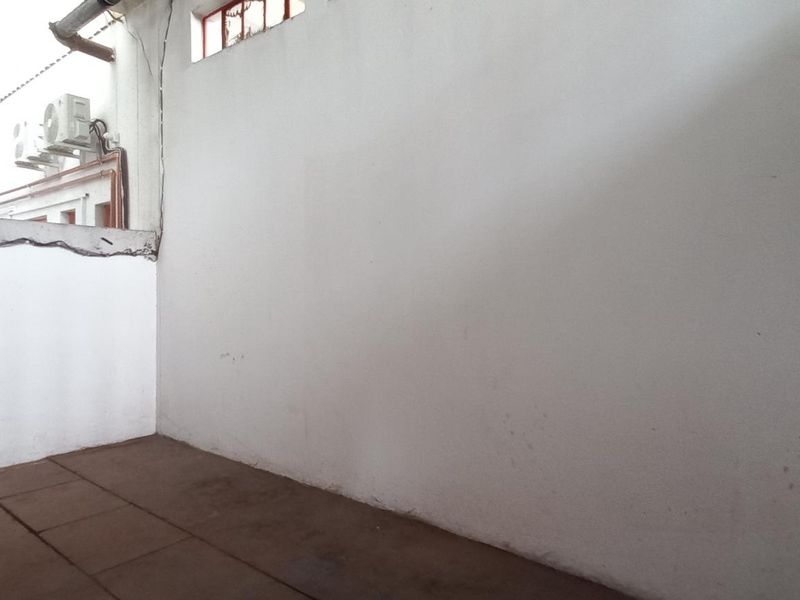 An empty utility or service area featuring tiled flooring, high-level windows, and wall-mounted air conditioning units, suitable for various industrial or storage purposes.