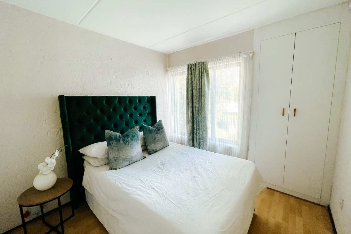 A cozy bedroom featuring built-in white cabinetry, light wood-look flooring, and a window with natural light.