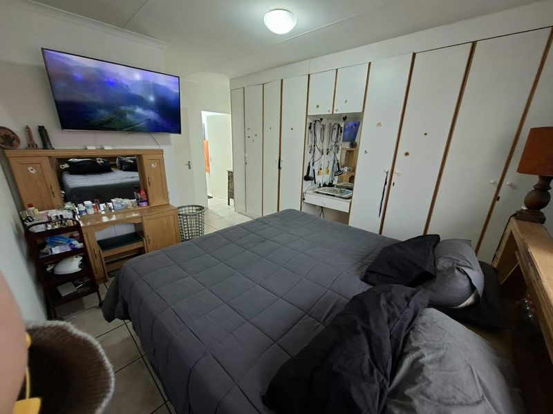 A bedroom featuring extensive built-in cupboard storage and tiled flooring, requiring cosmetic updates to the cabinetry and general finishes.