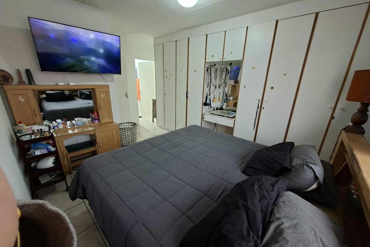 A bedroom featuring extensive built-in cupboard storage and tiled flooring, requiring cosmetic updates to the cabinetry and general finishes.
