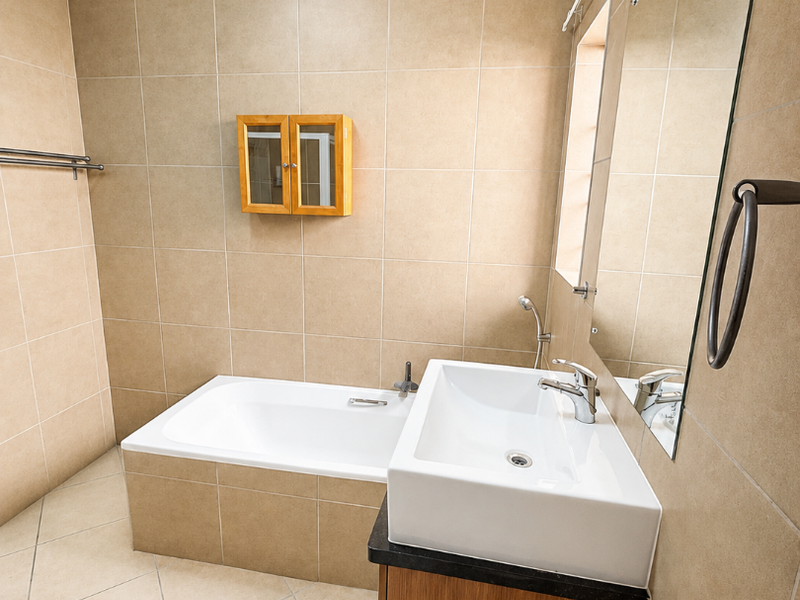 A clean, neutral-toned bathroom featuring a built-in bathtub, a modern vanity with a basin, and wall-mounted storage, offering a functional and well-maintained space.