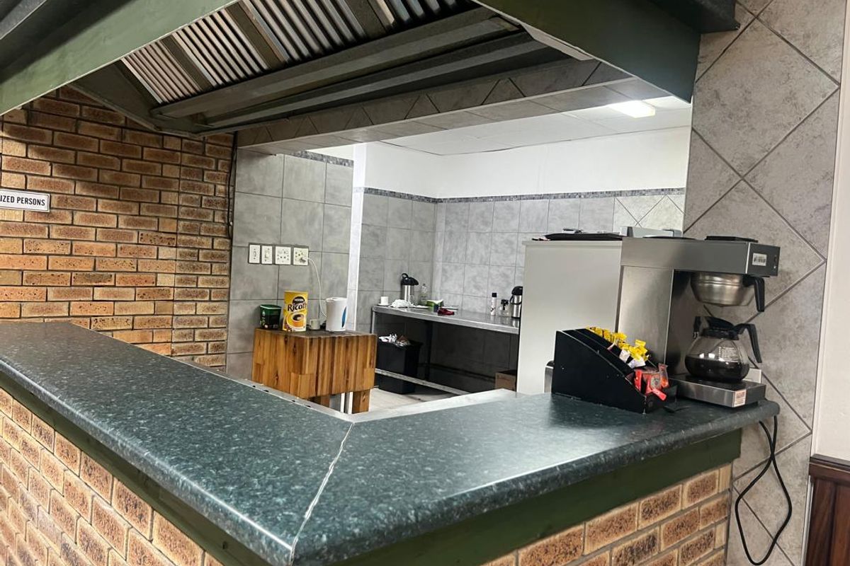 A functional commercial-style kitchen area featuring a brick service counter, stainless steel prep surfaces, and a large overhead extractor hood.
