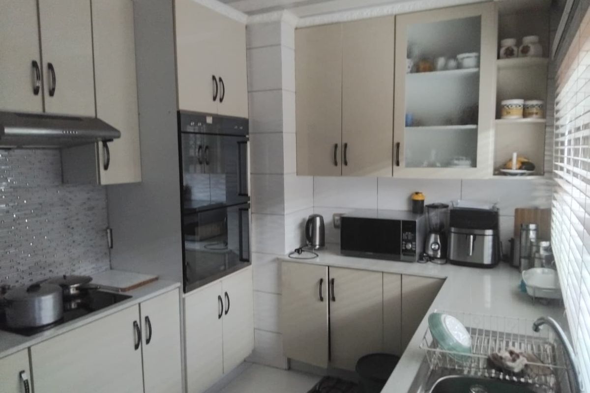 A functional kitchen featuring built-in cabinetry, a wall-mounted oven, extractor fan, and tiled backsplash with ample counter space.
