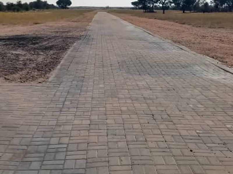 A long, paved driveway leading through the open farm landscape, providing clear access to the property grounds.