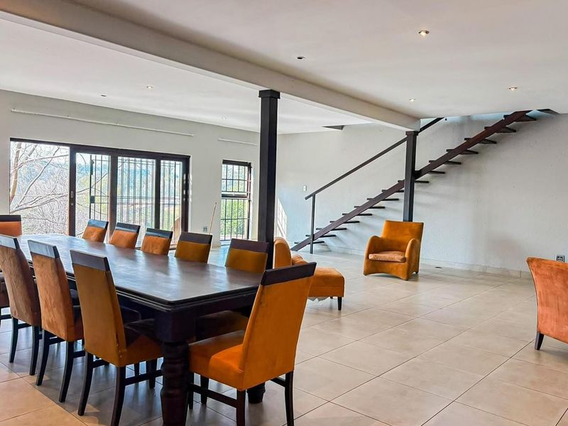 Spacious open-plan living and dining area featuring tiled floors, recessed lighting, and a modern metal staircase leading to the upper level.