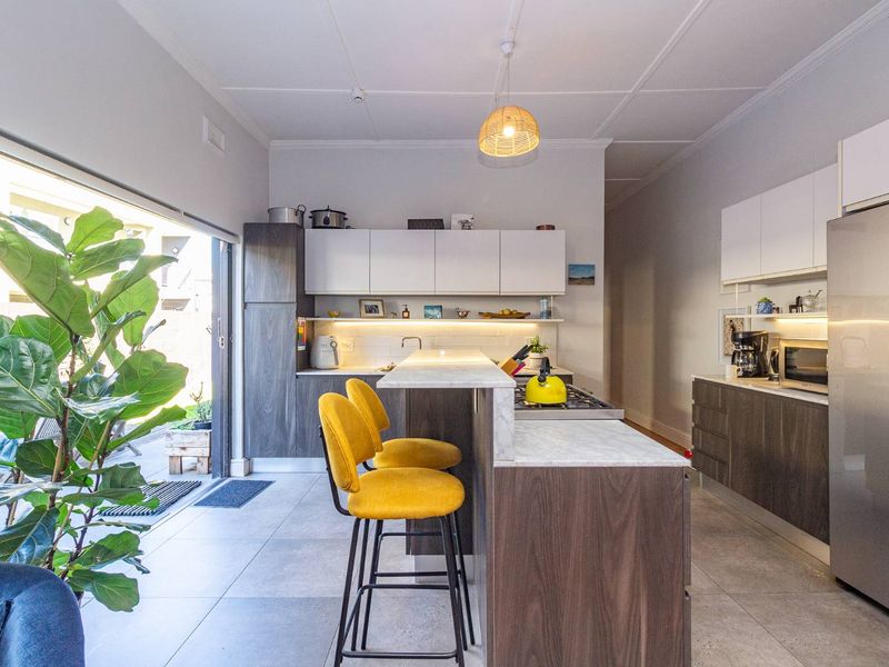 Modern kitchen featuring a central island with stone countertops, sleek built-in cabinetry, gas hob, and seamless access to the outdoor patio area.