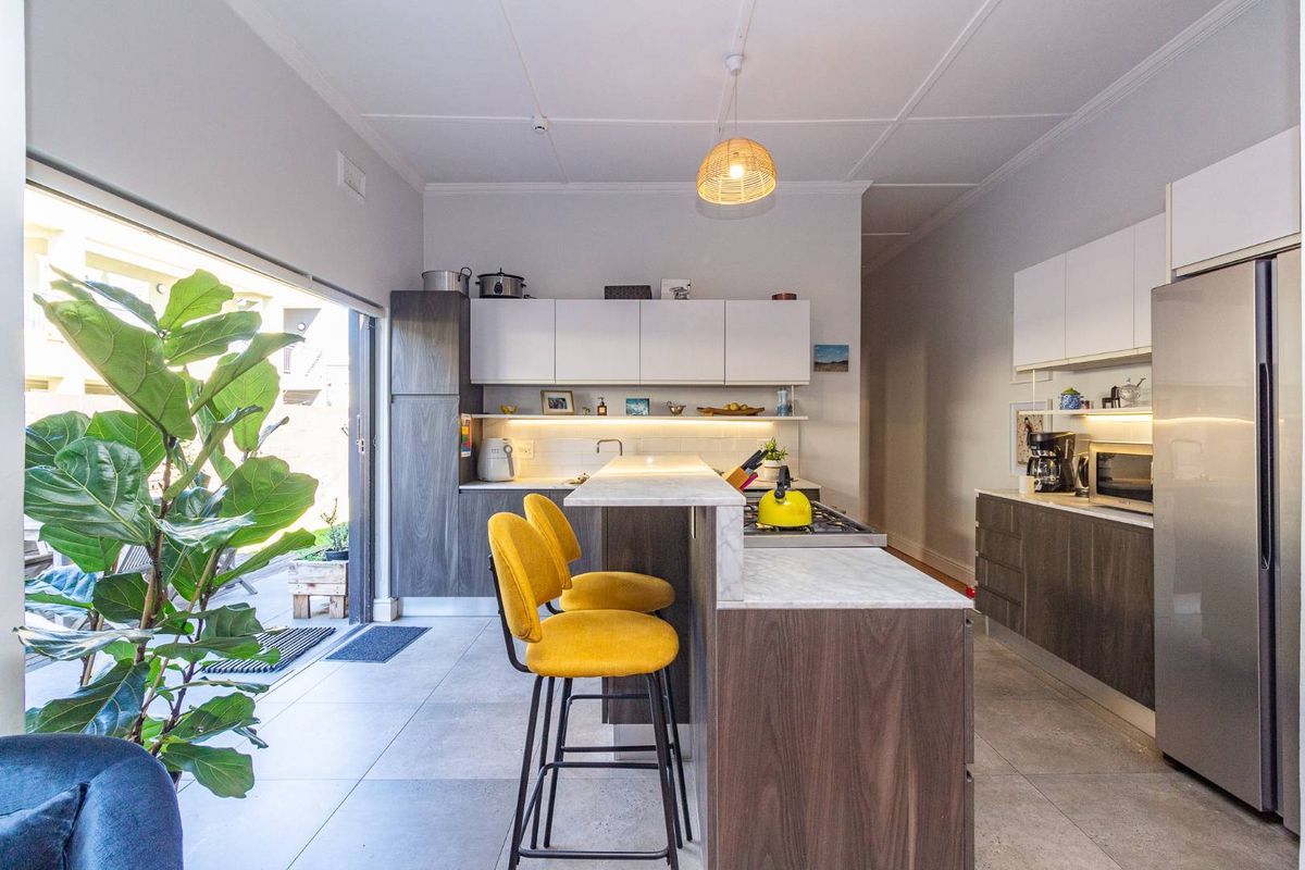 Modern kitchen featuring a central island with stone countertops, sleek built-in cabinetry, gas hob, and seamless access to the outdoor patio area.