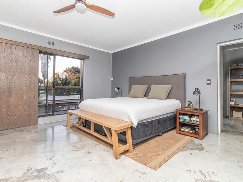 Spacious bedroom featuring polished concrete floors, a ceiling fan, large sliding doors, and an integrated walk-in closet area.