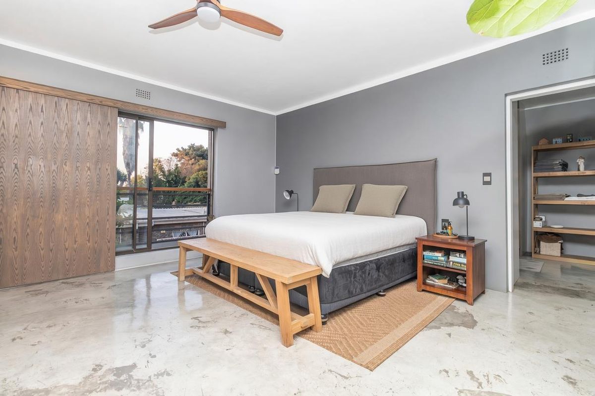 Spacious bedroom featuring polished concrete floors, a ceiling fan, large sliding doors, and an integrated walk-in closet area.