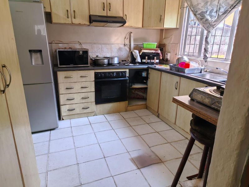 A functional kitchen featuring laminate cabinetry, built-in oven, extractor fan, and tiled flooring, offering potential for modernization and cosmetic updates.