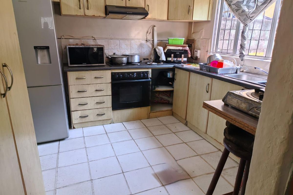 A functional kitchen featuring laminate cabinetry, built-in oven, extractor fan, and tiled flooring, offering potential for modernization and cosmetic updates.