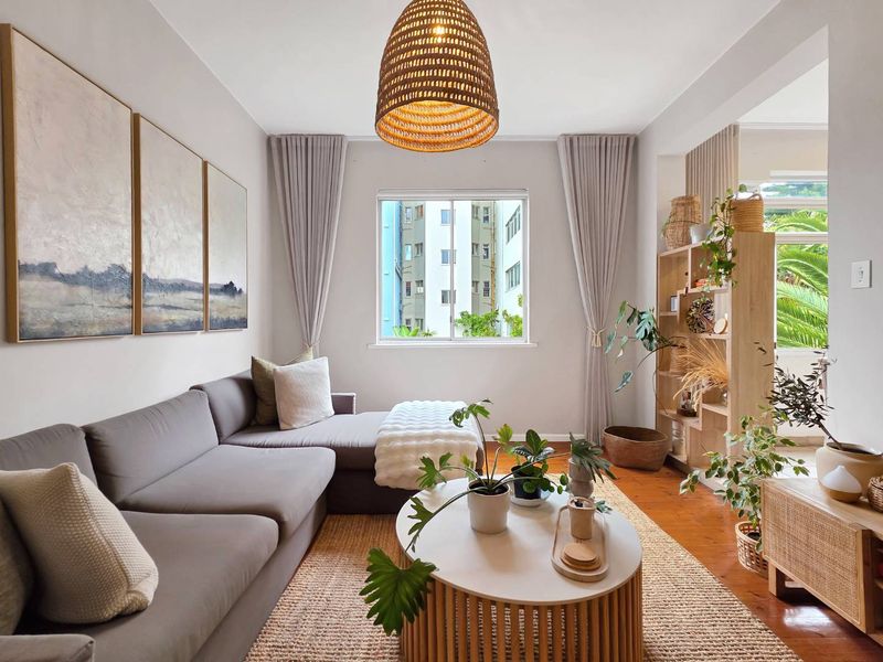 A bright and well-maintained living room featuring polished hardwood flooring and a large window, creating a warm and inviting atmosphere.