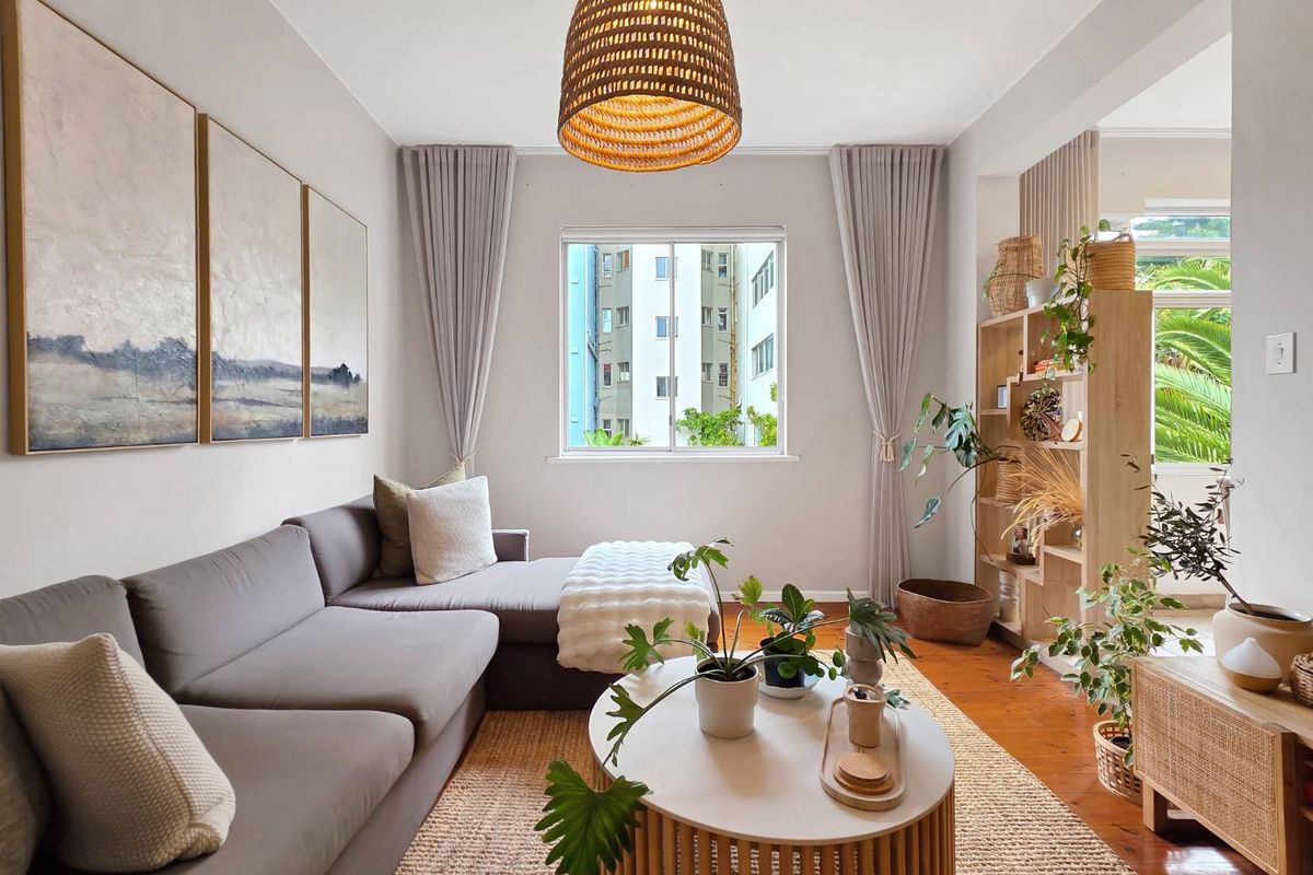A bright and well-maintained living room featuring polished hardwood flooring and a large window, creating a warm and inviting atmosphere.