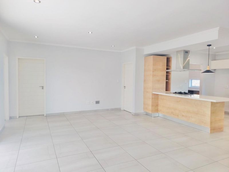Spacious open-plan living area featuring modern tiled floors, recessed lighting, and a contemporary kitchen with a built-in island, hob, and extractor fan.