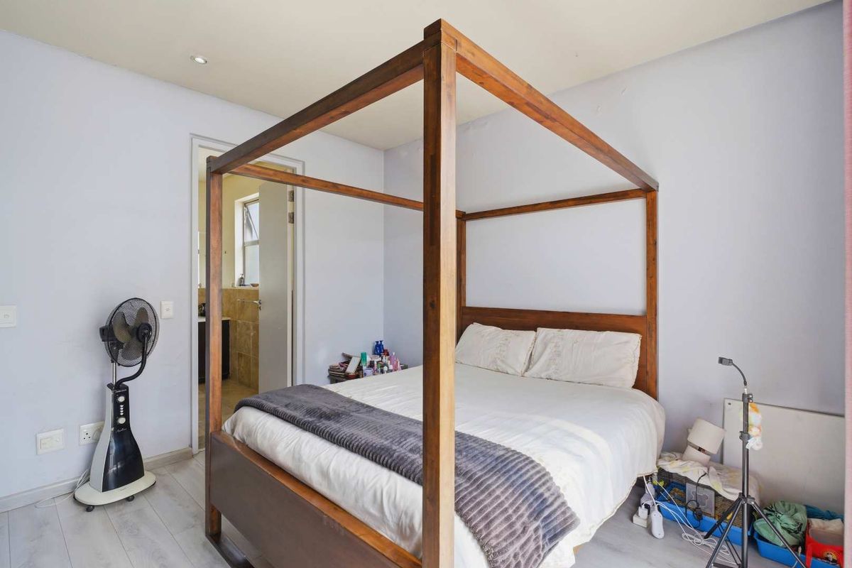 A bedroom featuring light-toned laminate flooring and an en-suite bathroom entrance.