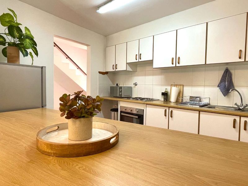 A functional kitchen featuring white cabinetry, laminate countertops, a built-in oven, and a tiled backsplash, with an adjacent breakfast bar area.