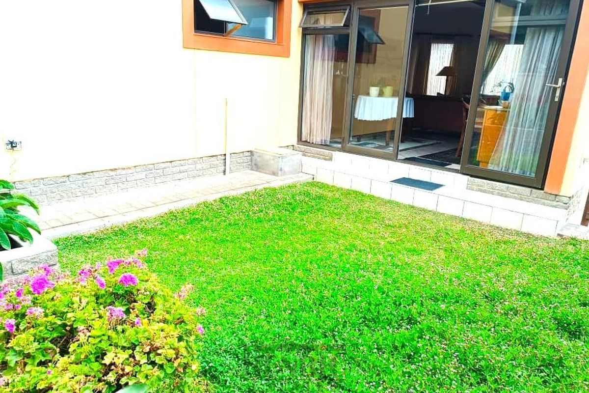 A view of the rear garden area featuring a small lawn and sliding glass doors providing access to the interior living space.