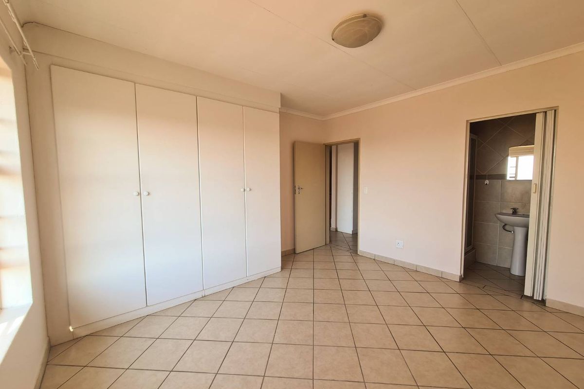 A bedroom featuring built-in wardrobes, tiled flooring, and an en-suite bathroom access point.