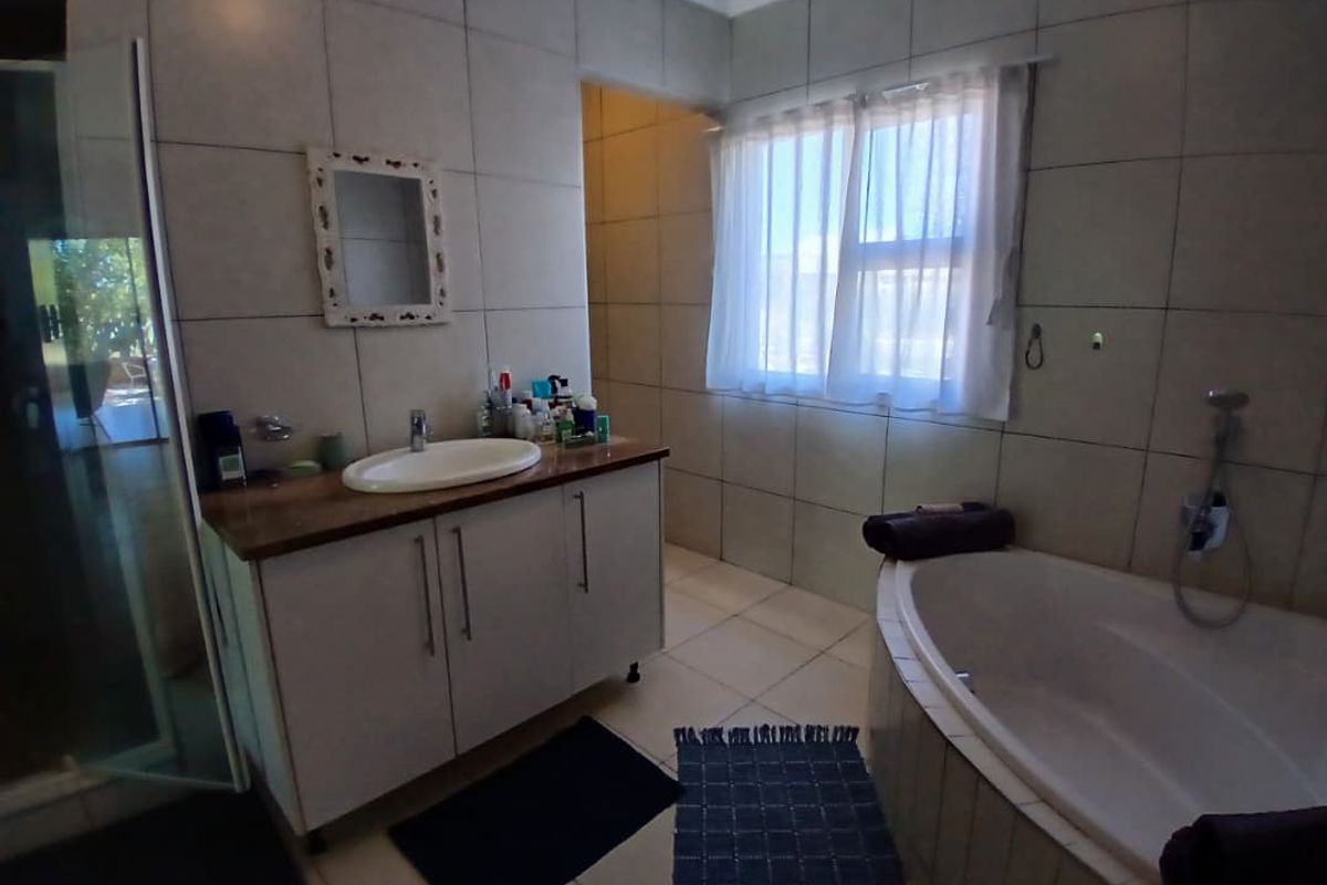 A functional bathroom featuring a vanity cabinet with a countertop basin, a built-in bathtub, and a separate shower enclosure with tiled finishes.