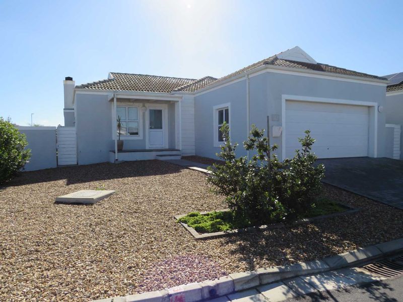 Front elevation of a single-story house featuring a tiled roof, attached garage, and low-maintenance gravel landscaping.