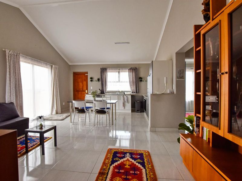 Spacious open-plan living and kitchen area featuring vaulted ceilings, polished tiled flooring, and direct access to the outdoors via sliding glass doors.
