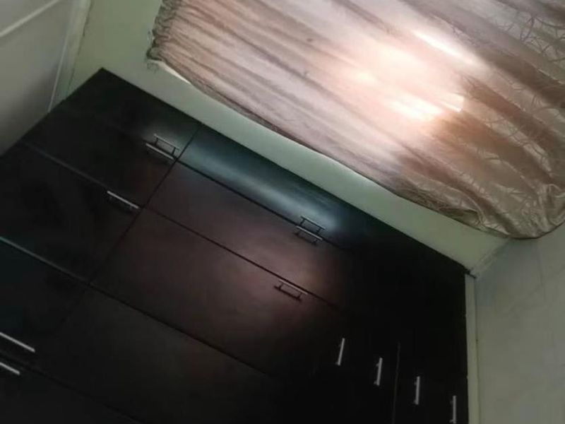 A bedroom featuring dark wood built-in cupboards and window treatments.