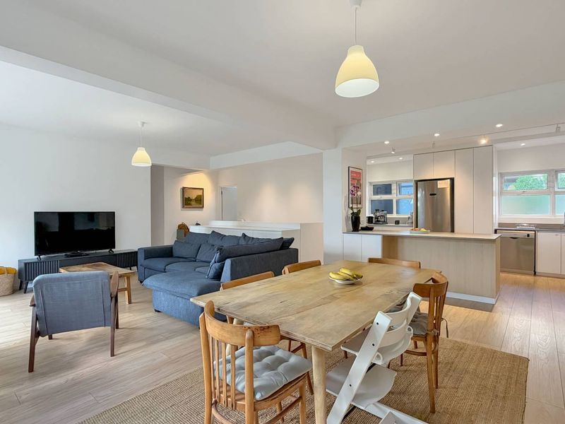 Spacious open-plan living, dining, and kitchen area featuring modern cabinetry, light wood-look flooring, and a functional layout ideal for contemporary apartment living.