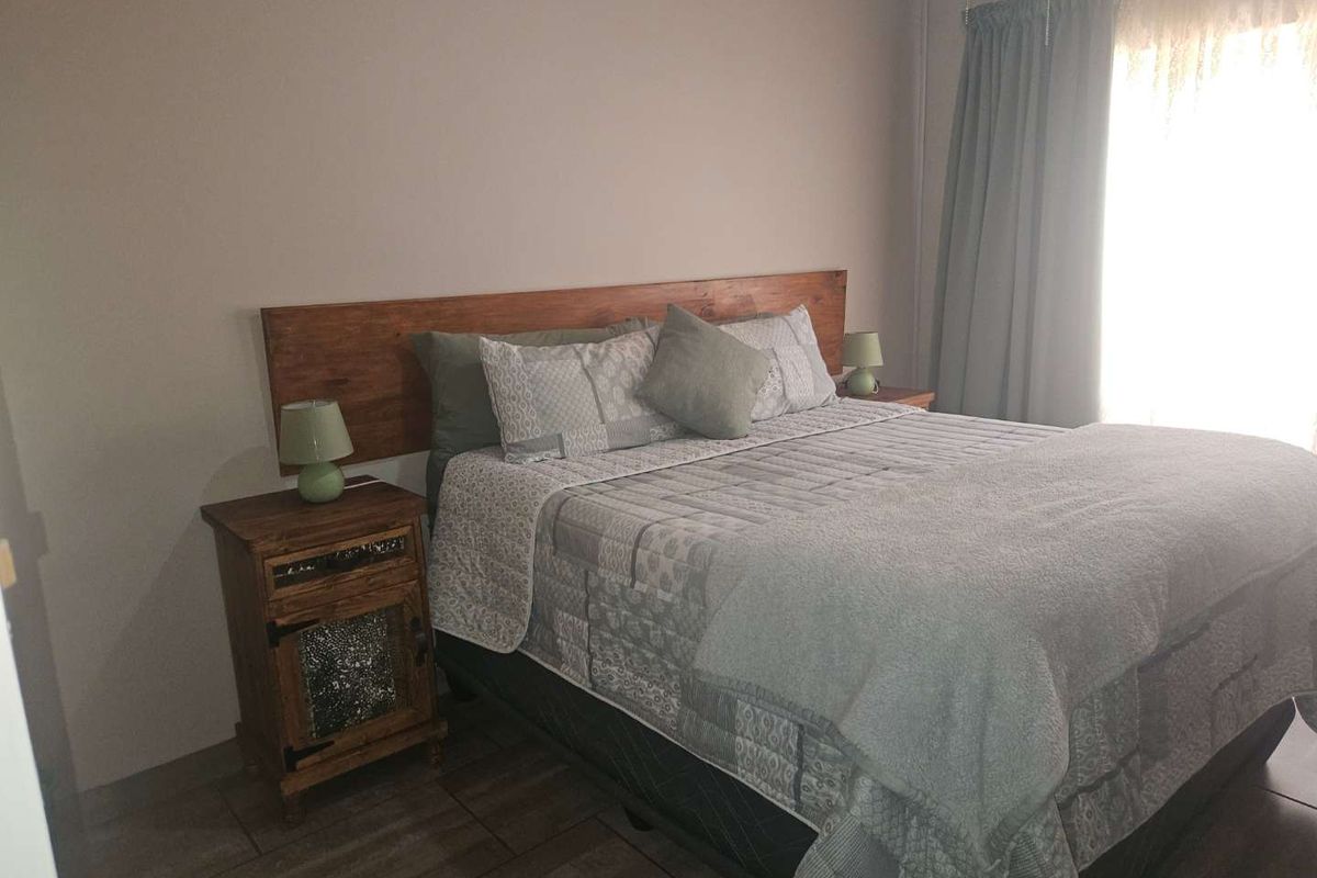 A bedroom featuring tiled flooring and a built-in wooden headboard, offering a neutral and functional space.