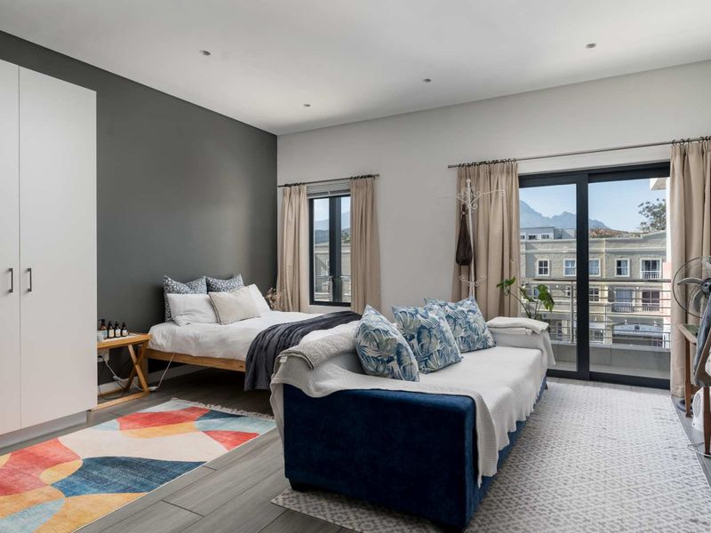 A well-lit bedroom featuring a built-in wardrobe, tiled flooring, and a sliding glass door providing access to a balcony with mountain views.