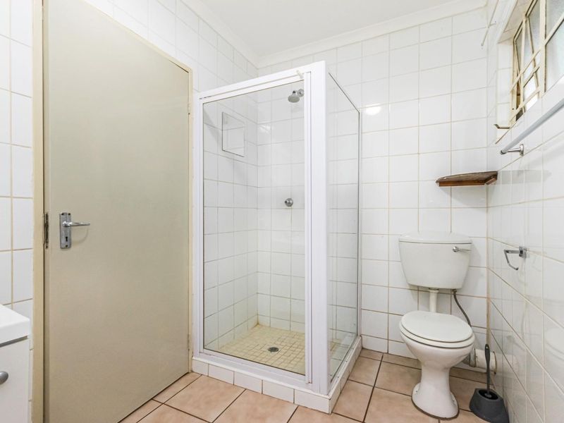 A functional bathroom featuring a shower enclosure, toilet, and tiled finishes throughout, offering a clean and practical space.