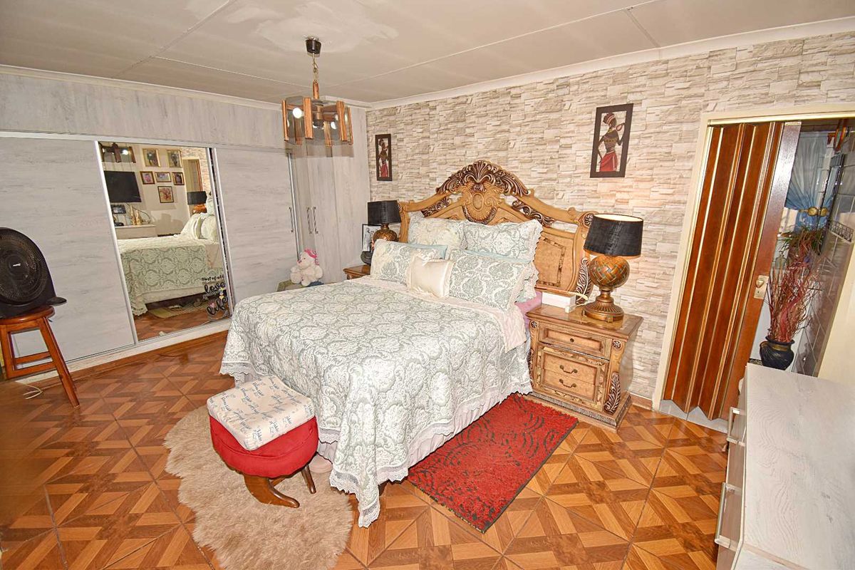A bedroom featuring patterned floor tiles, a built-in mirrored wardrobe, and a textured feature wall.