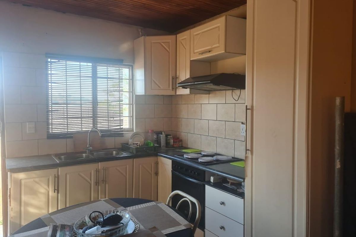 A functional kitchen featuring built-in cabinetry, a tiled backsplash, integrated hob and oven, and a distinctive timber ceiling.