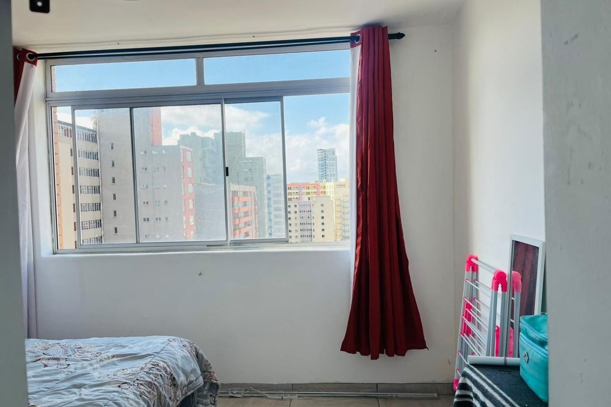 A bedroom featuring tiled flooring and a large sliding window with urban city views.